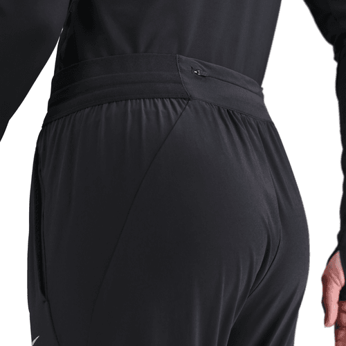 Nærbillede af en person iført Nike Dri-FIT Mid-Rise Running Pants, Dame, Black/Reflective Silv, med fokus på linning og baglomme. Ideel træningstøj dame til træning. Almindelig hvid baggrund.