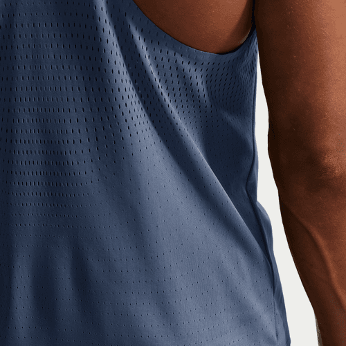 Nærbillede af en person iført Nike AeroSwift Running Singlet, Herre, i Diffused Blue/Black. Det ærmeløse, perforerede design ses fra siden og bagfra mod en almindelig lys baggrund.