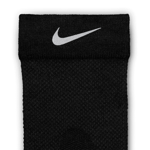 Et nærbillede af Nike Fast Wool Micro Crew Sock i Black/Dk Smoke Grey/Reflective Silv, der viser den hvide Swoosh nær manchetten og er fremstillet med Dri-FIT-teknologi mod en almindelig hvid baggrund.