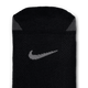 Nærbillede af Nike Fast Lightweight No Show unisex-strømper i sort/mørk røggrå med et gråt Swoosh-logo og to små grå trekantede manchetter. Strømperne har et åndbart, struktureret netlignende mønster.