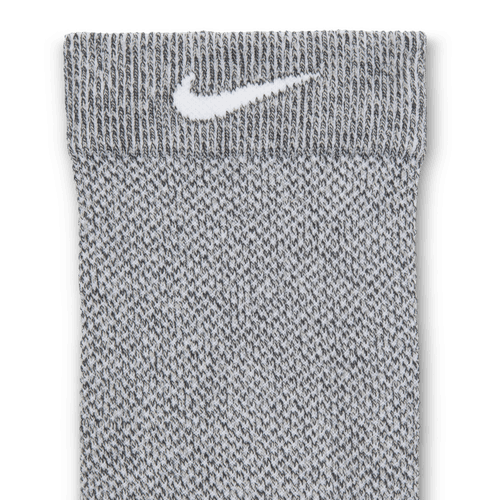 Et nærbillede af Nike Fast Lightweight Crew-strømpen i Dk Smoke Grey/Pure Platinum/White, unisex-model, der viser den strikkede tekstur og det hvide Swoosh-logo nær manchetten.