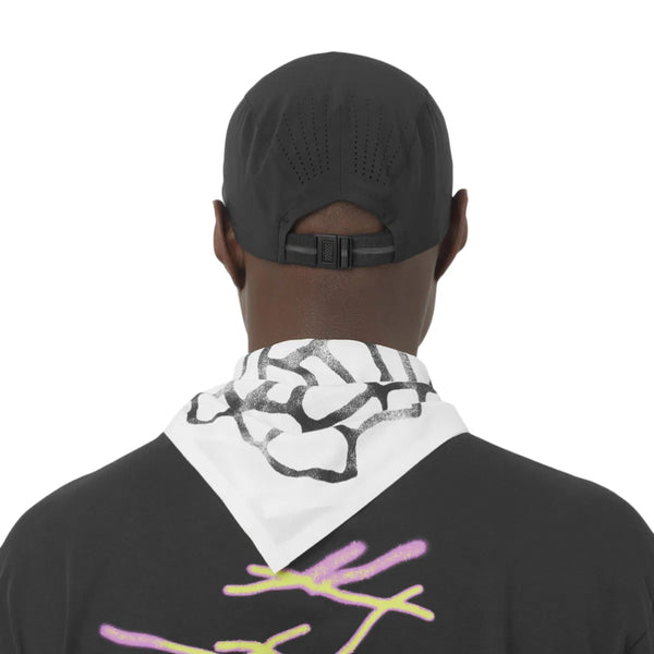 En person iført Salomon Shakeout Cap Unisex i Deep Black kigger væk fra kameraet med et hvidt tørklæde med et sort mønster og en sort skjorte med abstrakte farvede mønstre.