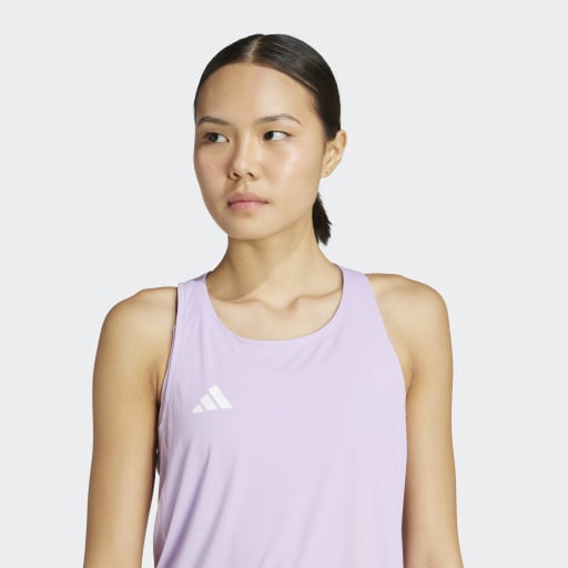 En kvinde med glat mørkt hår, der er bundet tilbage, er iført en ærmeløs lyslilla Adidas Adizero E Tank (Dame, Powplu) med et hvidt logo på brystet og står på en almindelig lys baggrund.