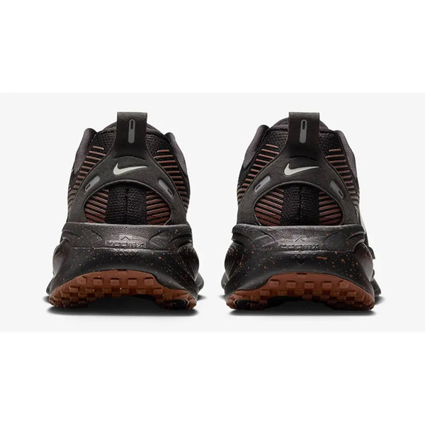Et par Nike Vomero 18 løbesko til herrer i Black/Ironstone-Velvet Brown vises bagfra med Nike-logo, teksturerede såler med ZoomX-skum og hæltræk mod en hvid baggrund.