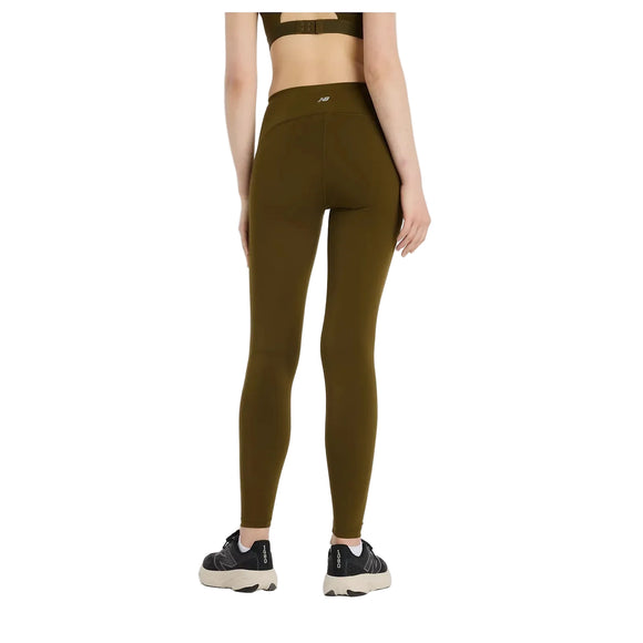 En person står væk fra kameraet i New Balance's Sleek Pocket High Rise Legging, Dame, Woodland, sammen med en matchende sports-bh og sorte sportssko med hvide såler på en almindelig hvid baggrund.