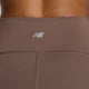 Nærbillede af den bagerste linning på brune Sleek Pocket High Rise Legging 27, Dame, Cortado fra New Balance. Det hvide logo ses over de synlige lodrette og vandrette sømme. En del af den øverste del af ryggen er synlig øverst i billedet.