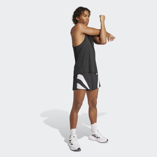 En person i sort tanktop, Adidas Adizero Archive Gel Shorts 3" (Herre, Sort), hvide sokker og hvide sportssko strækker armen ud over brystet mod en lysegrå baggrund.