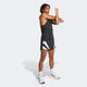 En person i sort tanktop, Adidas Adizero Archive Gel Shorts 3" (Herre, Sort), hvide sokker og hvide sportssko strækker armen ud over brystet mod en lysegrå baggrund.