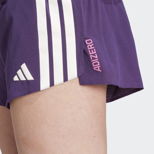 Nærbillede af en person iført Adidas Adizero Gel Dame Aurplu shorts i lilla med hvide striber, med "ADIZERO" i pink og et hvidt Adidas-logo på venstre side.