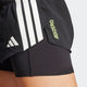 Nærbillede af en person iført Adidas Adizero 2I1 Shorts, Dame, Sort. Disse løbeshorts har hvide striber, gul ADIZERO-tekst, et lagdelt design med kompressionsmateriale og Adidas-logoet på venstre side.