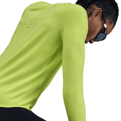 En kvinde i en lysegul Nike Dri-FIT UV Long-Sleeve Crew-Neck Running Top læner sig frem med sorte solbriller på, så man kan se en del af hendes flettede hår og ansigt fra en vinkel bagfra.