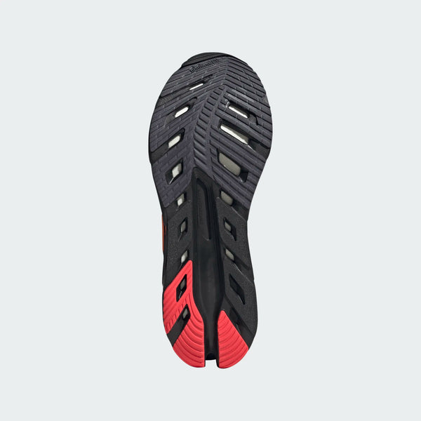 Billedet viser ydersålen på Adidas Adistar Byd, Herre, Cblack/Luor/Auon, med et slidbanemønster med riller og udskæringer; hælområdet er rødt, mens resten hovedsageligt er sort og gråt for optimal komfort.