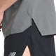 En person er vist fra underkroppen til låret iført en New Balance Race Day Ulitra Light T-shirt i Urgent Red og sorte New Balance-atletikshorts med slids i siden.