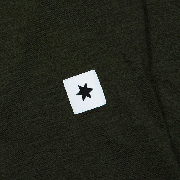 Nærbillede af Saysky Clean Pace Long Sleeve, Herre, Green, med en lille hvid firkantet patch med en sort sekstakket stjerne i midten.