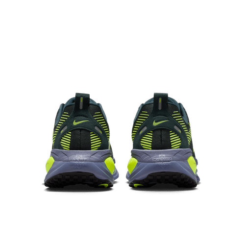 Et par Nike Vomero 18 Herre i Seaweed/Volt-Cannon-Sanded Purple vises bagfra på en hvid baggrund med en overdel i sort mesh og tykke, strukturerede såler med responsive ZoomX-mellemsål.