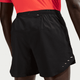 En person i en knaldrød skjorte og sorte Nike Stride 5" Brief-Lined Running Shorts, Herre, Black/Reflective Silv vises bagfra, hvor overbenene, taljen og den lille lynlåslomme bag på linningen fremhæves.