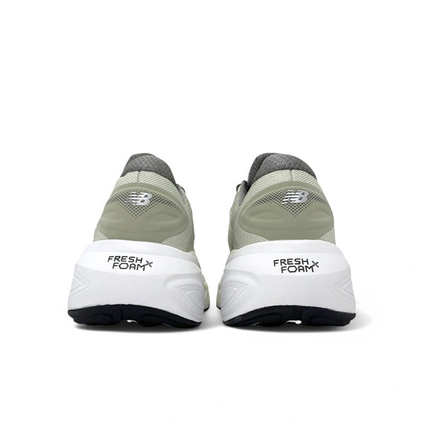 Et par lysegrå og hvide New Balance Freshfoam More V6, Herre, Mineral løbesko vises bagfra med logo på hælene, "Fresh Foam" på mellemsålerne for maksimal komfort og sorte såler.