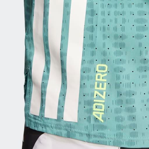 Nærbillede af den blågrønne Adidas Adizero Singlet Dame (Powtea/Pretea) med et diskret prikmønster, tre lodrette hvide striber og ADIZERO i gult. En hvid shorts titter frem forneden og viser denne ultralette løbetøj.
