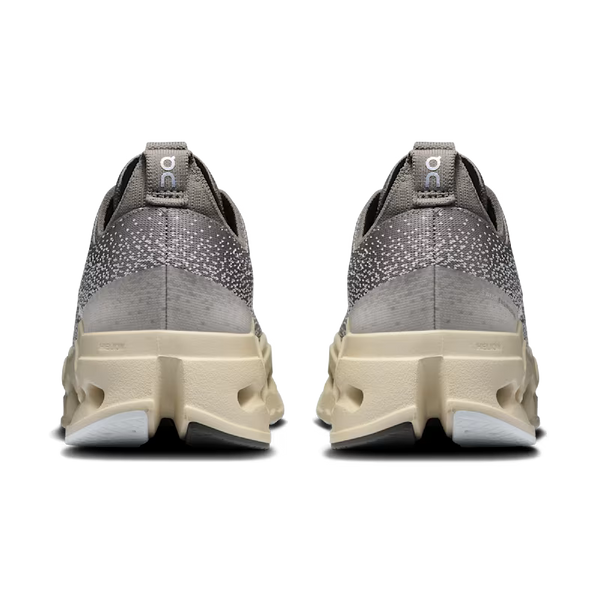 Et par On Cloudsurfer Max dame løbesko i Asphalt/Ice set bagfra, med en overdel i spraglet strik, trækflige ved hælen og chunky strukturerede beige såler.