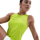 En kvinde iført Nike Dri-FIT Running Tank Top, Dame, Cyber/Reflective Silv og hvide shorts står på en hvid baggrund. Hun har en lille tatovering på armen og kigger til siden.