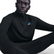 En person sidder på en hvid baggrund iført Nike Stride Dri-FIT 1/2-Zip Running Top for herrer i sort med en lille swoosh og planetgrafik på brystet.