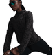 En kvinde strækker benet iført en sortmønstret Nike Dri-FIT løbejakke (Dame, Black/Anthracite/Reflective Silver) og sorte atletiske leggings. Hun bærer reflekterende solbriller og har håret trukket tilbage mod en hvid baggrund.