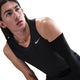 En person med langt brunt hår iført en ærmeløs sort Nike Dri-FIT Running Tank Top, Herre, Black/Reflective Silver og et sort kompressionsærme på højre arm kigger opad mod en almindelig hvid baggrund.