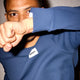 En person iført Saysky Motion Waffle Long Sleeve, Herre, Blue hæver armen og skjuler delvist ansigtet. Baggrunden er ensfarvet og lys-perfekt til løb eller aktive dage.