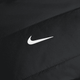 Nærbillede af det hvide Nike Swoosh-logo centreret på sort stof med synlige syninger på Nike Therma-FIT løbejakke til kvinder i Black/Reflective Silver.