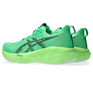 Asics Novablast 5 Dame i Vital Green/Black har tykke, plettede såler og trækflige i hælen. Disse løbesko giver et let og behageligt løb og er vist på en hvid baggrund.