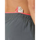 En person iført New Balance RC Ultra Light Split Short 3" i Urgent Red har en energigelpakke gemt bag på linningen.