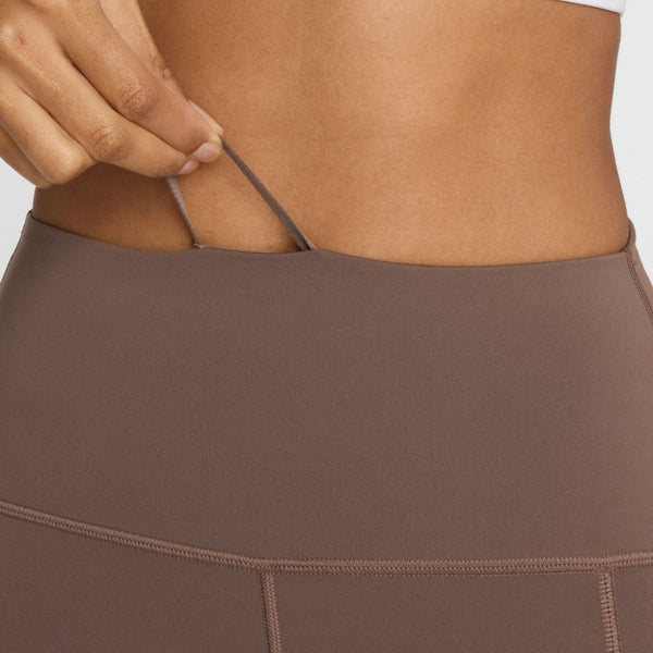 Nærbillede af en person iført New Balance Sleek Pocket High Rise Legging 27, Dame, Cortado-højtaljede træningstøj kvinder - med en hånd, der justerer den indvendige løbegang i linningen.