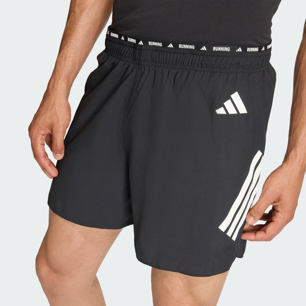 En person er iført sorte Adidas Adi365 Shorts, Herre med hvide striber og logoer og en elastisk linning med teksten "ADIDAS RUNNING". Kun underkroppen og lårene er synlige - ideelt til løb og fitness.