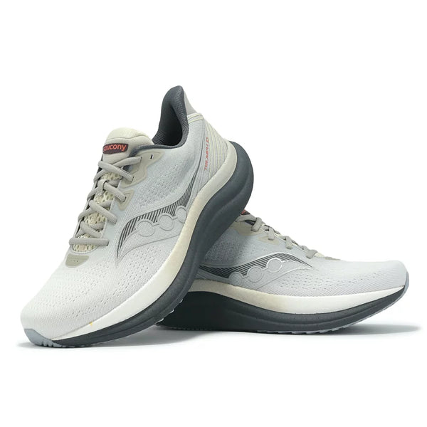Et par Saucony Triumph 23 Herre Grey/Shadow løbesko med lysegrå overdel og sorte såler og diskrete bølgemønstre, den ene stående og den anden lænet op ad den.