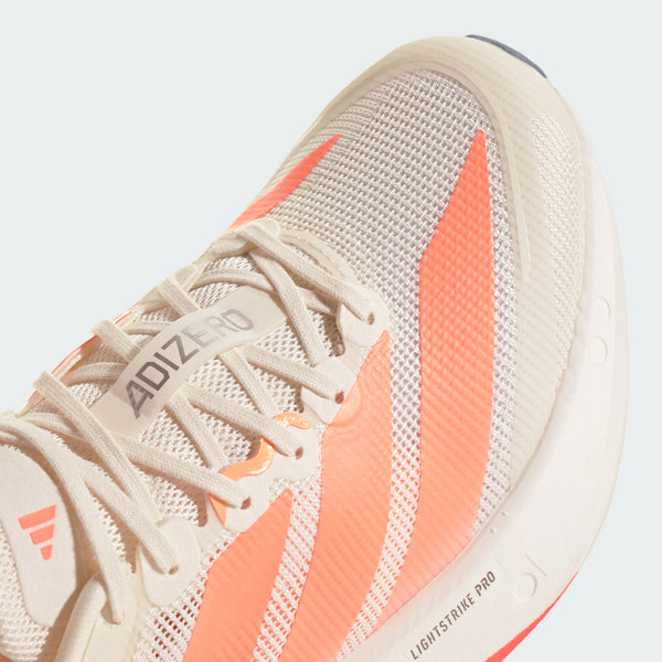 Nærbillede af Adidas Adizero Boston 13 løbesko dame i Owhite/Beaora/Aciora med mesh-overdel, koralfarvede striber, hvide snørebånd, ADIZERO-label på tungen og avanceret LIGHTSTRIKE PRO-støddæmpning i mellemsålen.