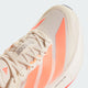 Nærbillede af Adidas Adizero Boston 13 løbesko dame i Owhite/Beaora/Aciora med mesh-overdel, koralfarvede striber, hvide snørebånd, ADIZERO-label på tungen og avanceret LIGHTSTRIKE PRO-støddæmpning i mellemsålen.