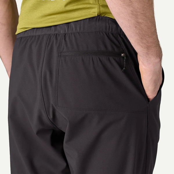 Et nærbillede bagfra viser en person iført Patagonia Terrebonne Joggers, Herre, Black-vandafvisende bukser med en baglomme med lynlås - sammen med en grøn skjorte for et stilfuldt og funktionelt look.