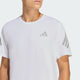 En mand er iført en Adidas Adi365 Running Tee, Herre, Hvid med lysegrå geometriske logoer på brystet og ærmerne, fotograferet fra skuldrene og op mod en ensfarvet baggrund.