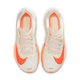 Et par Nike Zoom Fly 6 Dame løbesko i Pale Ivory/Hyper Crimson med hvid mesh-lignende overdel, orange og neongule detaljer, hvide snørebånd og en responsiv kulfiberplade for forbedret performance, set fra oven.