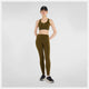 En kvinde ser fremad i New Balance's Sleek Pocket High Rise Legging i Dame Woodland, sammen med en matchende sports-bh, sorte sneakers og en sort kasket på en almindelig hvid baggrund.