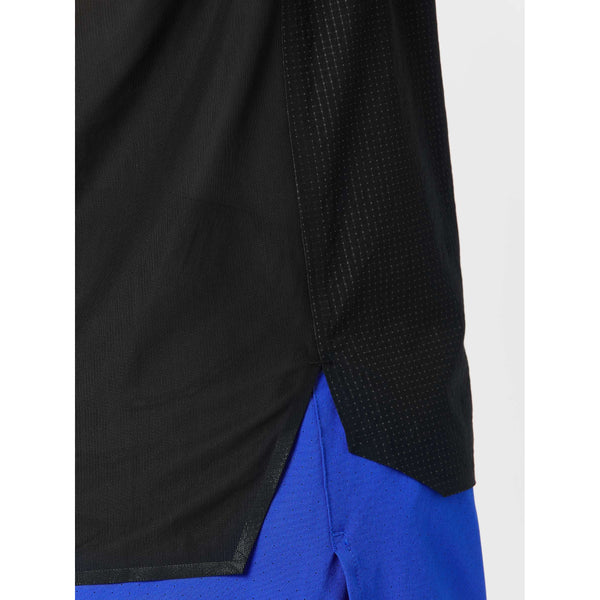 Nærbillede af den nederste halvdel af New Balance Race Day Ultra Light Singlet, Herre, sort med små perforeringer og slids i siden, sammen med lyseblå perforerede sportsshorts - perfekt til løbsdagen.