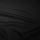 Nærbillede af Saysky Mesh Base Layer Long Sleeve (Unisex, sort) med et subtilt cirkulært prikmønster og diagonale folder. Lyset fremhæver det strukturerede, åndbare design - perfekt til løb eller som langærmet basislag.