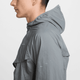 Sidebillede af en person iført Nike Repel UV Running Jacket, Herre i Smoke Grey/Smoke Grey/Reflective Silv, der kun viser hovedet og overkroppen mod en hvid baggrund. Personen vender mod venstre.