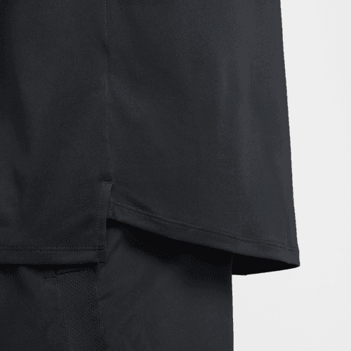 Nærbillede af kanten på Nike Stride SS Løbetop til mænd i sort/reflekterende sølv med slids i siden og overlappende detaljer over sorte bukser på en almindelig hvid baggrund.
