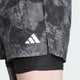 Nærbillede af en mands overben iført Adidas Otr Sd 2In1 M shorts i Grefou/Black, lagt over sorte kompressionsshorts - ideelle 2-i-1 træningsshorts til herrer.