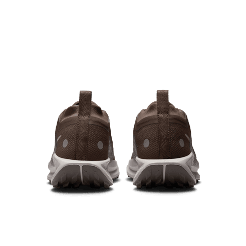 Et par Nike Pegasus Trail 5 Gore-Tex Dame-sko i Ironstone/College Grey-Velvet Brown, vist bagfra med hvide såler og cirkulære hælmarkeringer på en ensfarvet lysegrå baggrund.