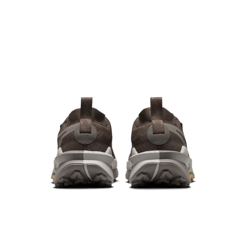 Et par Nike Zegama 2 Herre trailsko i Ironstone/Cave Stone-College Grey vist bagfra på en almindelig hvid baggrund, med teksturerede såler for tekniske stier og trækflige i hælen.