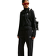 En person iført en sort Nike Therma-FIT 1/2-Zip Top, Dame, sort/Summit White, med matchende bukser og en rygsæk.