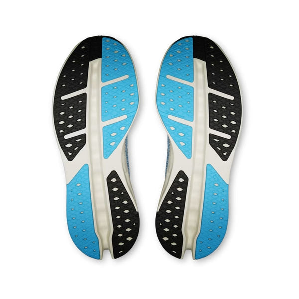 Billedet viser sålerne på et par On Cloudsurfer Max, Herre, Dust/Ivory. Blå, sorte og hvide sektioner med små huller og riller fremhæver den avancerede CloudTec-teknologi, som giver optimalt greb. Skoene er placeret side om side.