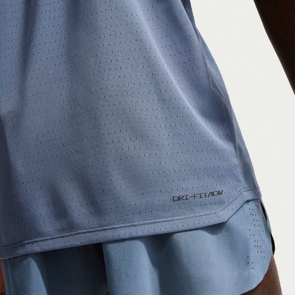 Nærbillede af en person i en Nike Dfadv Aroswft Ss Top, Herre, Diffused Blue/Black løbetop med svedtransporterende materiale. Kun en del af overkroppen og armen er synlig; et lille DRI-FIT ADV-logo ses nær kanten.